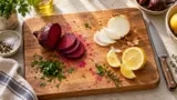 Tábua de madeira com manchas de beterraba e ingredientes cortados sobre a bancada